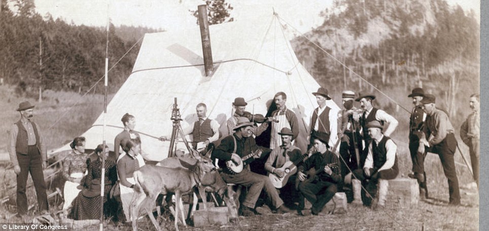 Happy band: Mining engineers with their wives and a couple of tame deer get together for an impromptu campside musical concert
