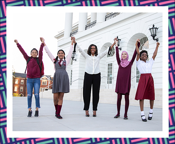 Mrs. Obama stands with arms raised with 4 girls from around the world.