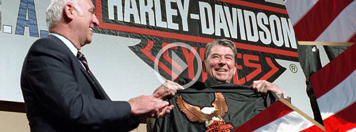 President Reagan during a trip to York, Pennsylvania and a visit to the Harley-Davidson motorcycle plant and holding up a gift of a jacket.