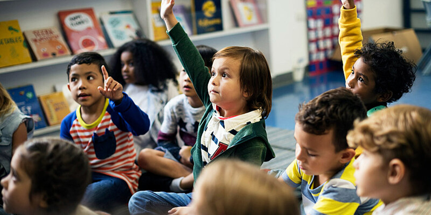 Children raising their hands during a class.