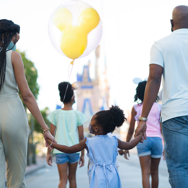 A family of five walks toward Cinderella Castle while mom and dad are hand-in-hand with their youngest daughter.