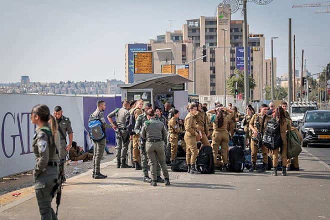 Israeli soldiers wait for a bus at the entrance to Jerusalem, Oct. 8, 2023. Photo by Noam Revkin Fenton/Flash90.