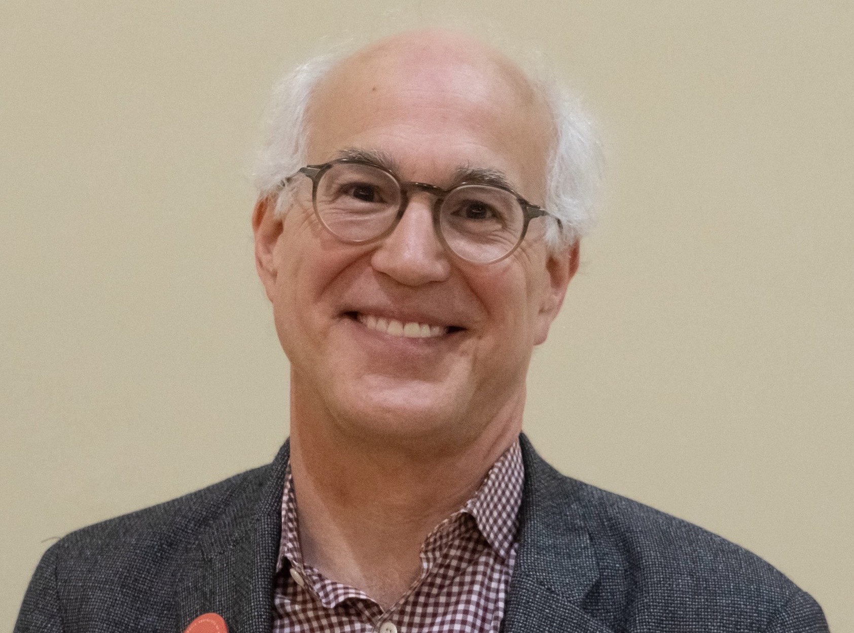 Bespectacled smiling white man with white hair.