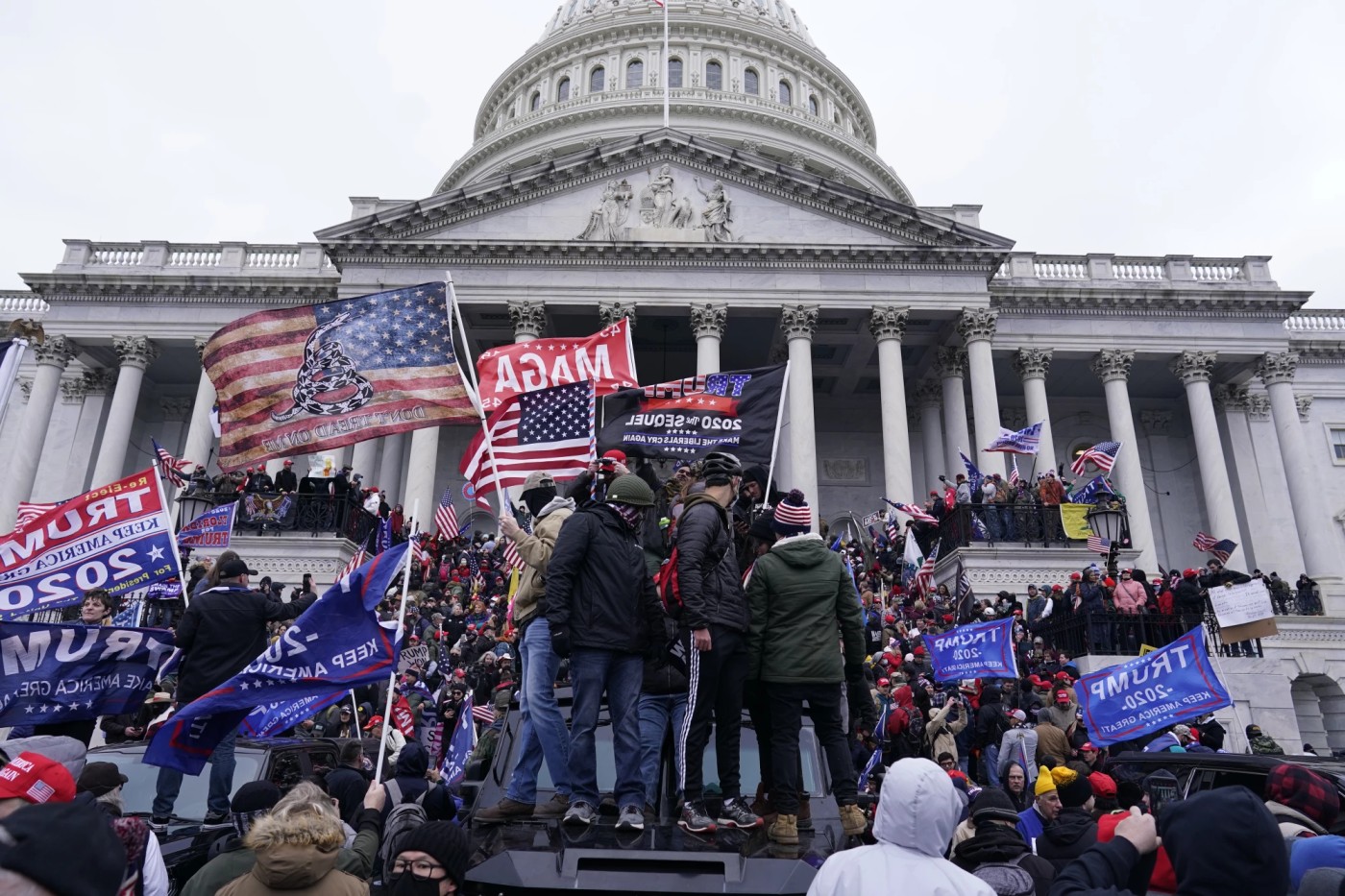 Jan. 6th Insurrectionists wave Trump flags as they climb the steps of the Capitol