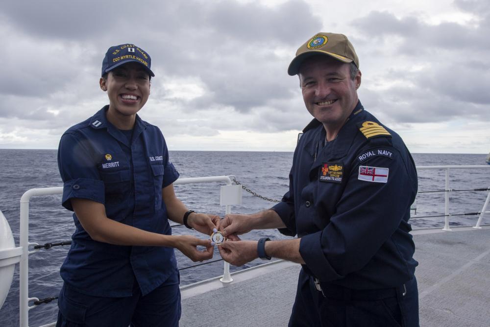 Capt. Charles Maynard of the Royal Navy, serving as deputy mission commander of Pacific Partnership (PP22), right, receives a U.S. Coast Guard challenge coin from Lt. Jalle Merritt, commanding officer of USCGC Myrtle Hazard (WPC 1139) 