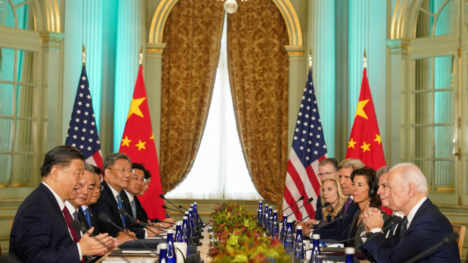 Presidents Biden and Xi sit across from one another during a meeting.