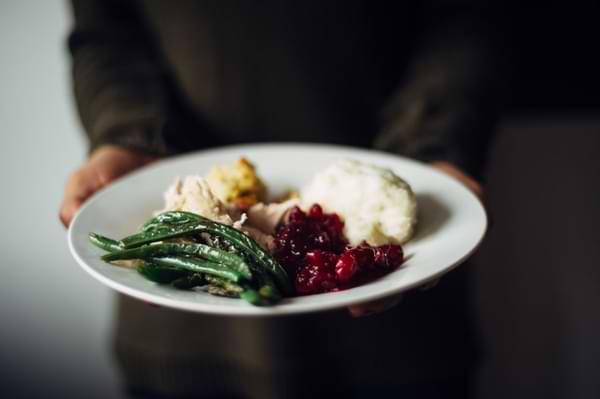 A woman holds a plate of Thanksgiving dinner. © By Laura/stock.adobe.com