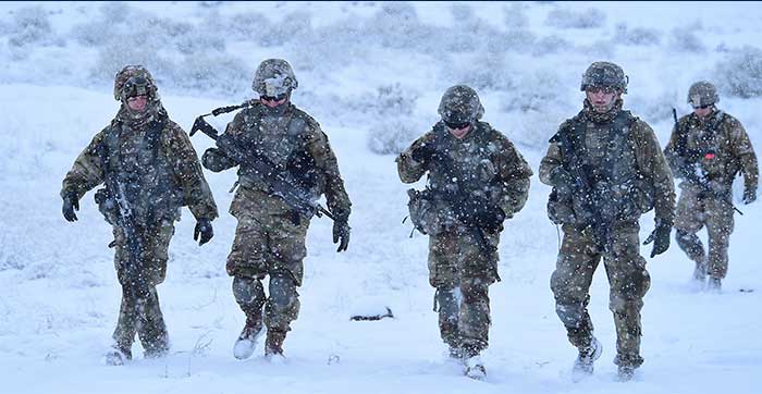 5 service members walking through snow falling in uniform 5 service members walking through snow falling in uniform