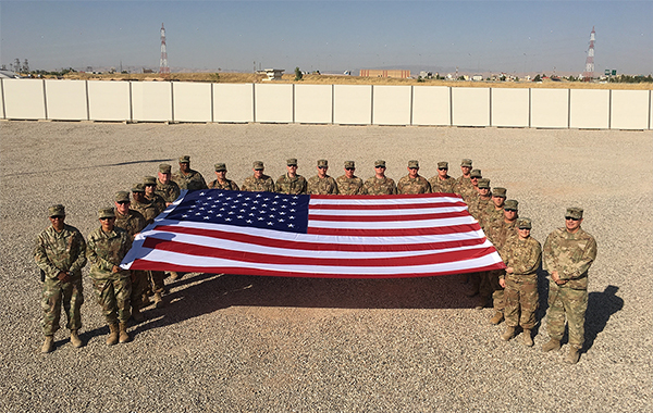 Service members stand with the flag. Service members stand with the flag.
