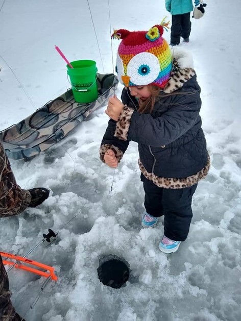 Young girl ice fishing with colorful owl hat