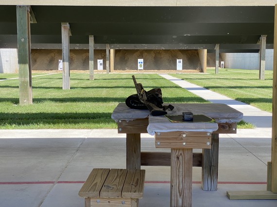 A gun sitting on a bench at a shooting range, with targets in the background.