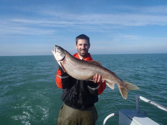 A man holding a large lake trout with both hands.