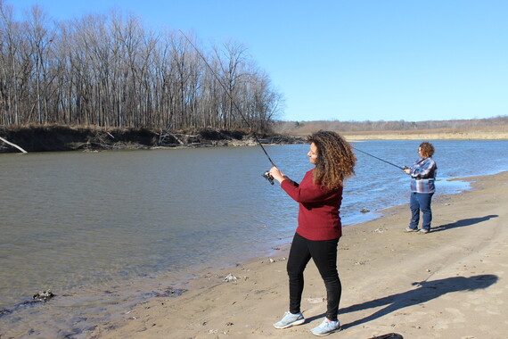 A woman fishing on the shore.