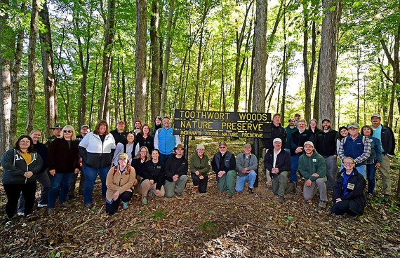 DNR staff posing beside Toothwort Woods Nature Preserve’s sign.