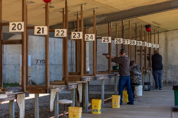 Three men in a row and shooting at a shooting range.
