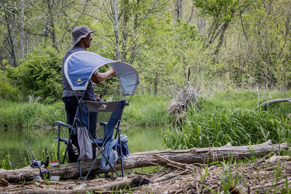 A man smiling as he fishes by the water.