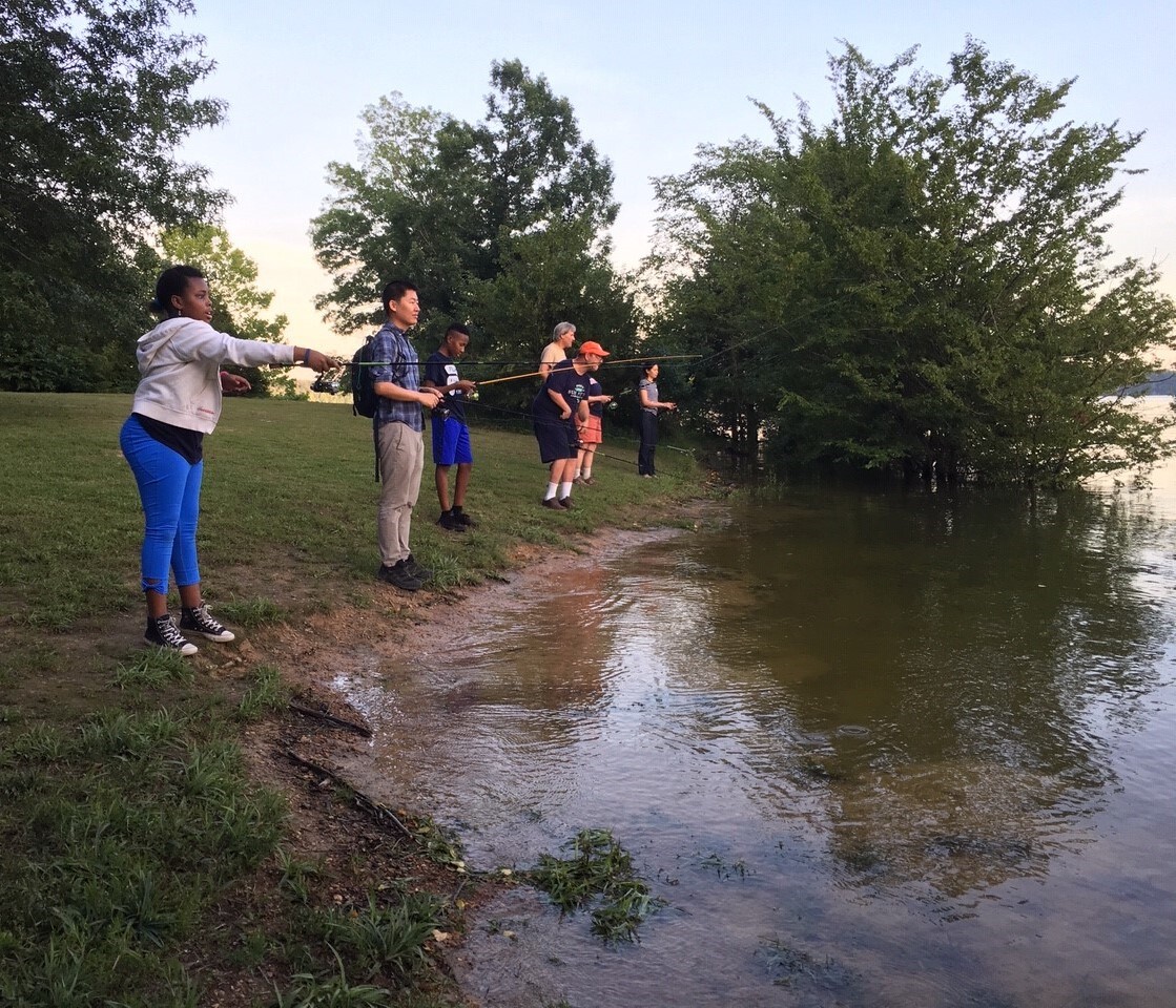 A group of people fishing as they stand on a shore.
