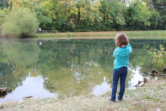 A young girl fishing on the shore.