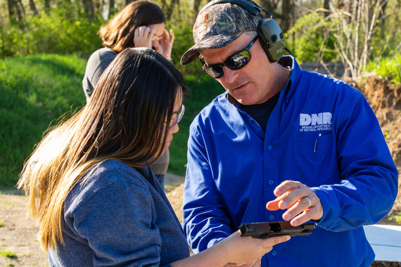 A DNR staff member working with a customer at a shooting range.