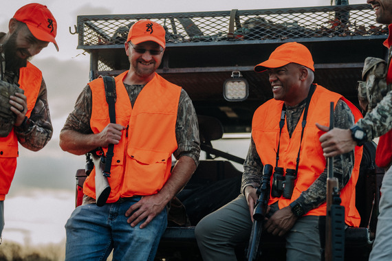 Three hunters speaking with one another and smiling.