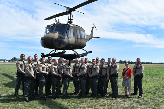 A group of the new Conservation Officer Academy graduates in front of a helicopter