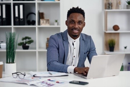 Black male in suit at laptop smiling