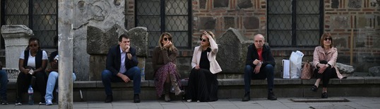 photo of four people sitting on a raised pavement on a street