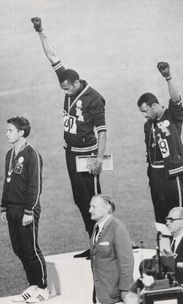 3 man standing on podium after track race, two are raising a fist in the air