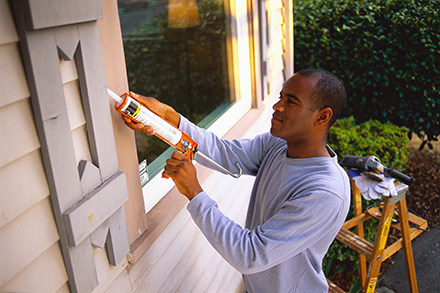 Man sealing windows on home