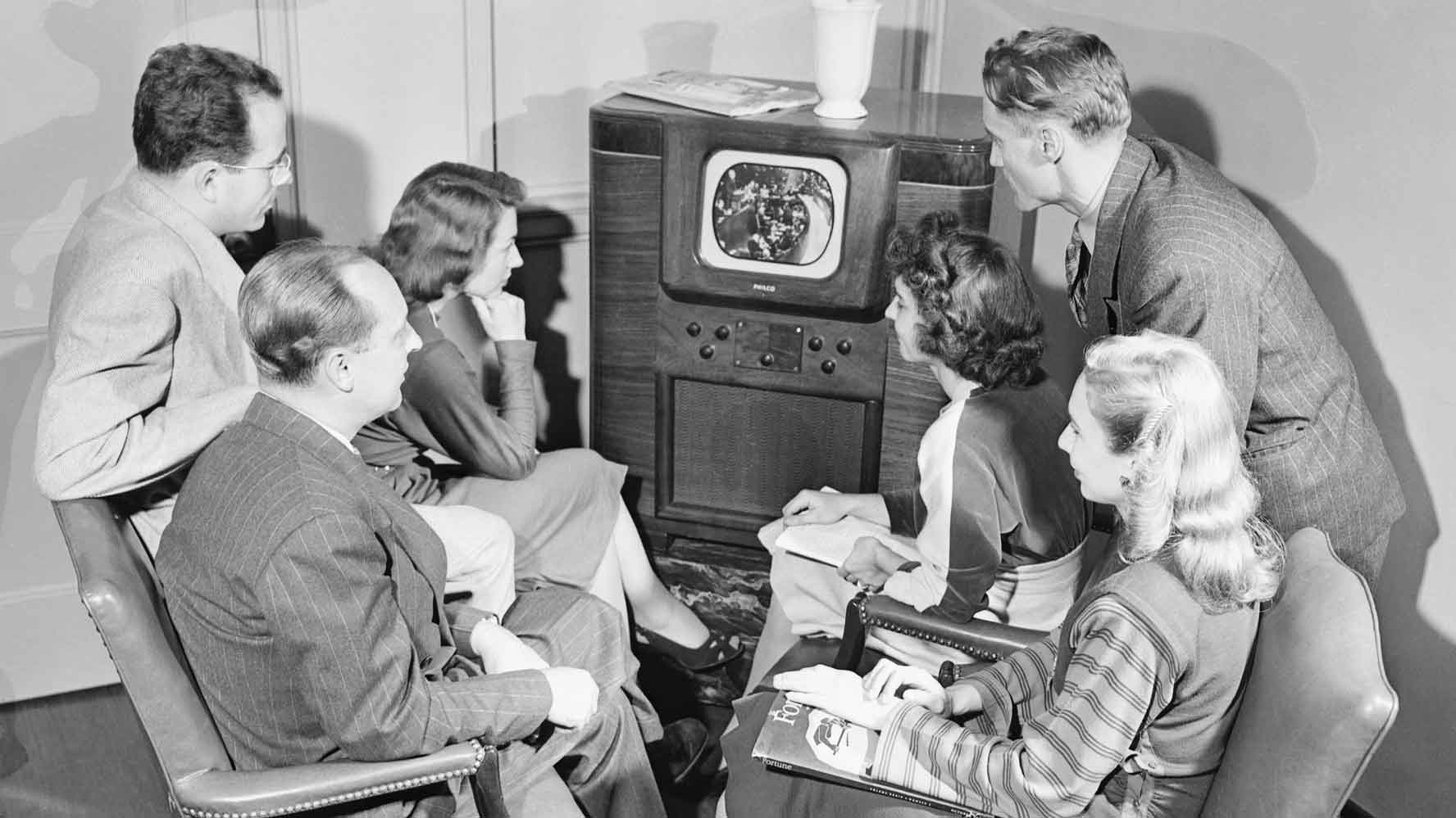 People gathered around a television set.