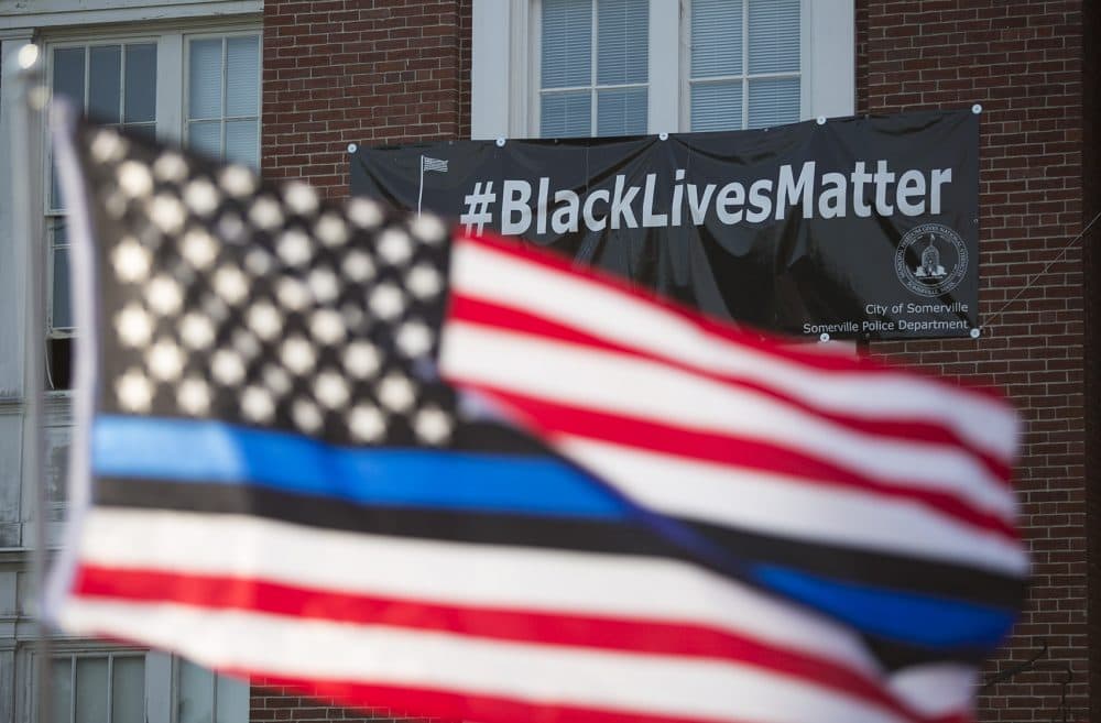 A Thin Blue Line flag waves in front of the Black Lives Matter banner at Somerville City Hall. (Jesse Costa/WBUR)