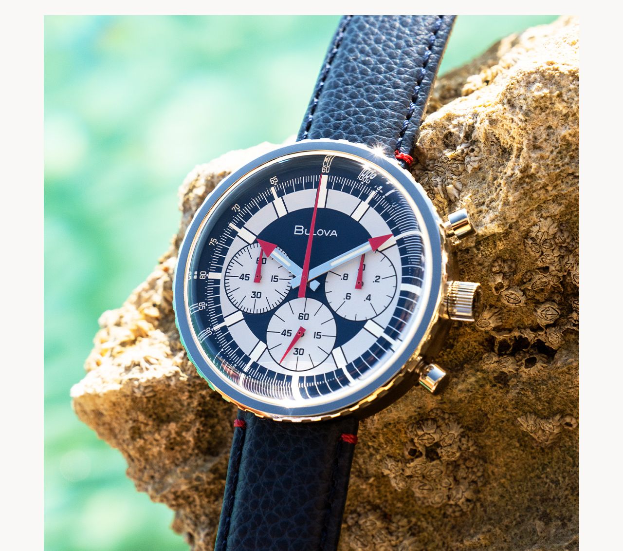 A men's Chronograph C in a silver-tone stainless steel case with iconic blue and white dial, red accents complemented by a blue leather strap with red safety stitching and deployant buckle closure.