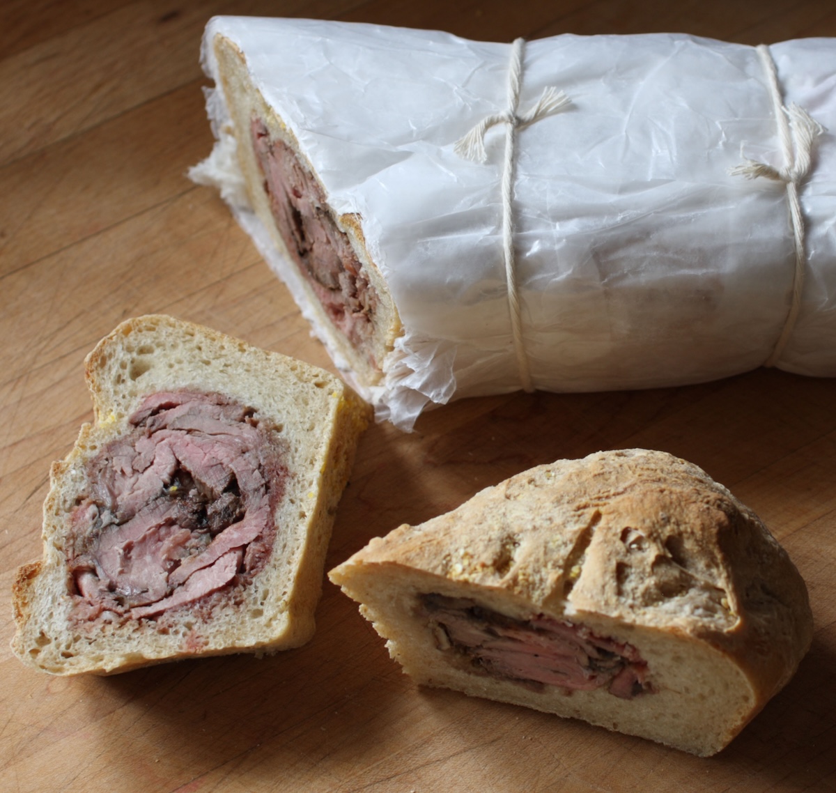 A wrapped sandwich, with some slices to show that it's filled with meat