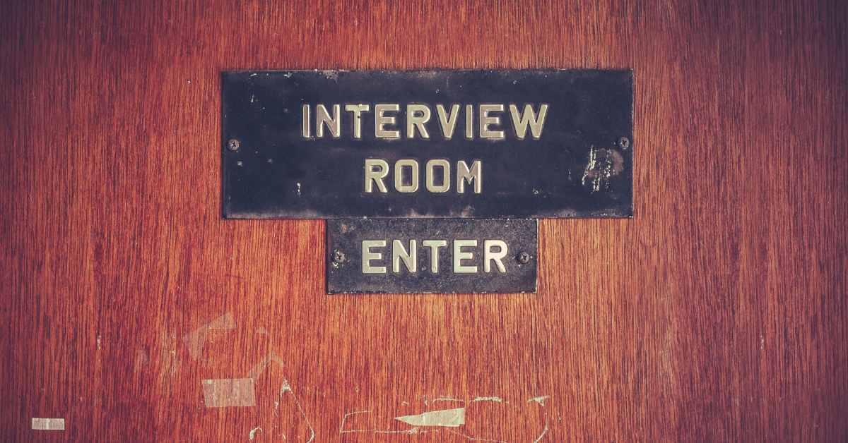 An old door with two signs that read 'Interview Room' and 'Enter'