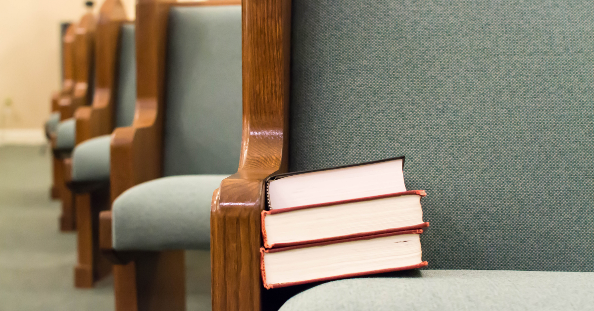 A stack of books sitting at the end of a church pew
