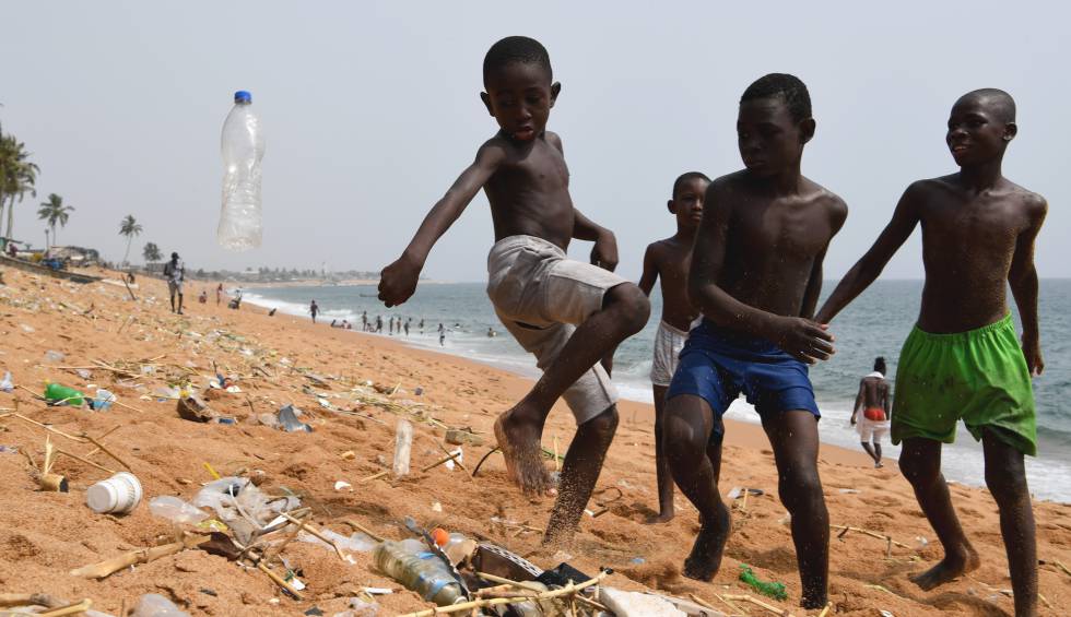 Un grupo de niños juega con una botella de plástico en una playa de Costa de Marfil.