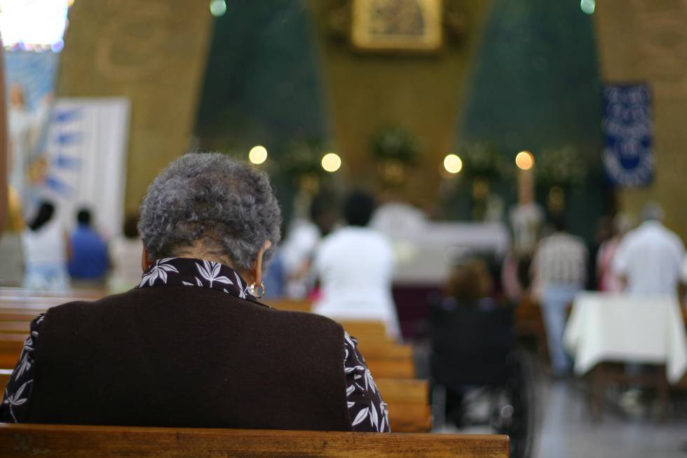 Una mujer reza sentada en un banco de una Iglesia catlica.