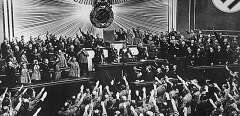 German Nazi chancellor Adolf Hitler (C) receives an ovation from the Reichstag and members of parliament who give him the nazi salute, for the “Anschluss” with Austria, the "peaceful" acquisition of Austria, in March 1938 in Berlin. (Photo by HO / THE NATIONAL ARCHIVES / AFP)