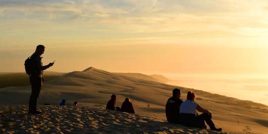 People watch the sunset on top of the dune of Pilat (or Pyla), the highest sand dune in Europe, on November 23, 2017 at La Teste-de-Buch in the Arcachon bassin, southwestern France. (Photo by Nicolas TUCAT / AFP)