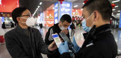 This photo taken on February 28, 2020 shows a passenger wearing a face mask as he shows a green QR code on his phone to show his health status to security upon arrival at Wenzhou railway station in Wenzhou. - The National Health Commission on March 1 reported 573 new infections, bringing the total number of cases in mainland China to 79,824. (Photo by NOEL CELIS / AFP)