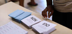 A voter looks at ballot papers as people arrive to vote in the referendum on New Caledonia's independence from France in Noumea, on the French overseas territory of New Caledonia, on November 4, 2018. - The French Pacific islands of New Caledonia were voting on November 4 on whether to become an independent nation, in a closely-watched test of support for France in one of its many territories scattered around the globe. (Photo by Theo Rouby / AFP)