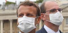 TOPSHOT - French President Emmanuel Macron (C) and French Prime Minister Jean Castex both wearing a protective facemask react at the end of the annual Bastille Day military ceremony on the Place de la Concorde in Paris, on July 14, 2020. - France holds a reduced version of its traditional Bastille Day parade this year due to safety measures over the COVID-19 (novel coronavirus) pandemic, and with the country's national day celebrations including a homage to health workers and others fighting the outbreak. (Photo by Ludovic Marin / POOL / AFP)