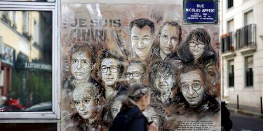 (FILES) A file photo taken on August 31, 2020 shows woman walking past a painting by French street artist and painter Christian Guemy, known as C215, in tribute to members of Charlie Hebdo newspaper who were killed by jihadist gunmen in Paris on January 2015. - Officers arrested the suspected attacker after four people were injured in a knife assault in Paris on September 25, 2020, near the former offices of satirical weekly Charlie Hebdo, French police said. The man was arrested near the sprawling Place de la Bastille, police said, adding he was the only suspect in an attack that came as a trial is under way for alleged accomplices in the January 2015 attack on Charlie Hebdo that killed 12 people. (Photo by THOMAS COEX / AFP) / RESTRICTED TO EDITORIAL USE - MANDATORY MENTION OF THE ARTIST UPON PUBLICATION - TO ILLUSTRATE THE EVENT AS SPECIFIED IN THE CAPTION