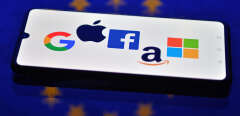 An illustration picture taken in London on December 18, 2020 shows the logos of Google, Apple, Facebook, Amazon and Microsoft displayed on a mobile phone with an EU flag displayed in the background. (Photo by JUSTIN TALLIS / AFP)