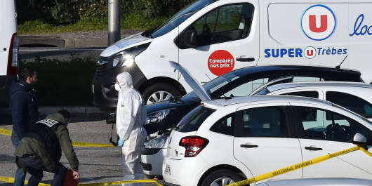 A French forensic officer waits to inspect a vehicle (C hood up) believed to belong to the hostage taker and parked outside the Super U supermarket in the town of Trebes, southern France on March 23, 2018. - Security forces killed a gunman who first hijacked a car in nearby by Carcassonne, killing a passenger and injuring the driver, before shooting a policeman who was out jogging with his colleagues nearby. He then drove to a Super U supermarket in the town of Trebes and holed up there for more than three hours with hostages, killing at least two other people, according to sources. (Photo by PASCAL PAVANI / AFP)