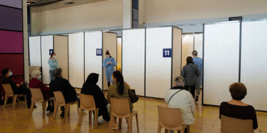 People wait outside booths for their turn to be vaccinated at a Covid-19 vaccination centre, located at the Conference centre in Nice, during the third lockdown weekend implemented to curb the spread of the novel coronavirus, in the French riviera city of Nice, southern France, on March 13, 2021.