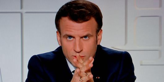 French President Emmanuel Macron is seen on a TV screen as he speaks during a televised address on the new Covid-19 restrictions from the Elysee Palace in Paris on March 31, 2021. (Photo by Ludovic MARIN / AFP)