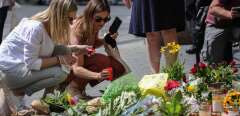 Two women place a candle at a makeshift memorial of flowers and candles in tribute to the victims of a deadly attack in the city center of Wuerzburg, southern Germany, on June 26, 2021. - Investigators were racing to pinpoint the motive of a man who went on a knife rampage in the German city of Wuerzburg, killing three people and leaving five seriously injured. The suspect, a 24-year-old Somali who arrived in Wuerzburg in 2015, staged the attack in the city centre on the evening of Friday, June 25, 2021, striking at a household goods store before advancing to a bank. (Photo by ARMANDO BABANI / AFP)
