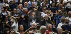 Audience members hols a posterof French far-right media pundit Eric Zemmour as he delivers a speech as part of his promotional tour for his book "France hasn't said its last word" (La France nía pas dit son dernier mot) in Beziers, southwestern France on October 16, 2021.