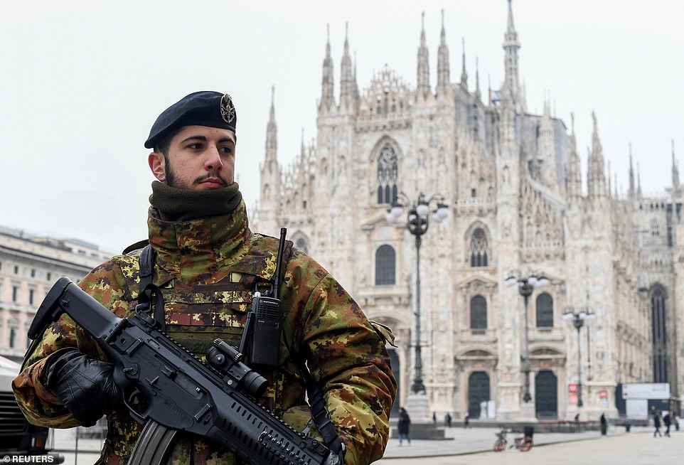 A soldier holds his gun near the Duomo cathedral in Milan this morning with the whole of Italy now in lockdown
